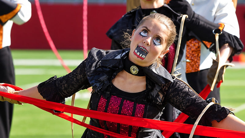 Theatrical color guard performer using red puppet strings as part of a field performance.
